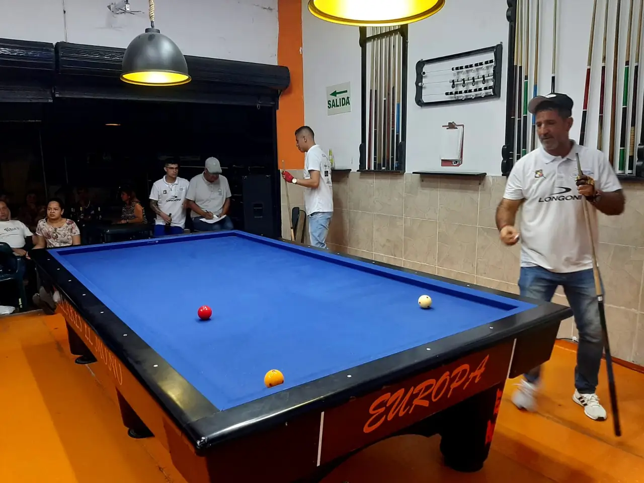 Jugador junto a la mesa de paño azul con las tres bolas en juego