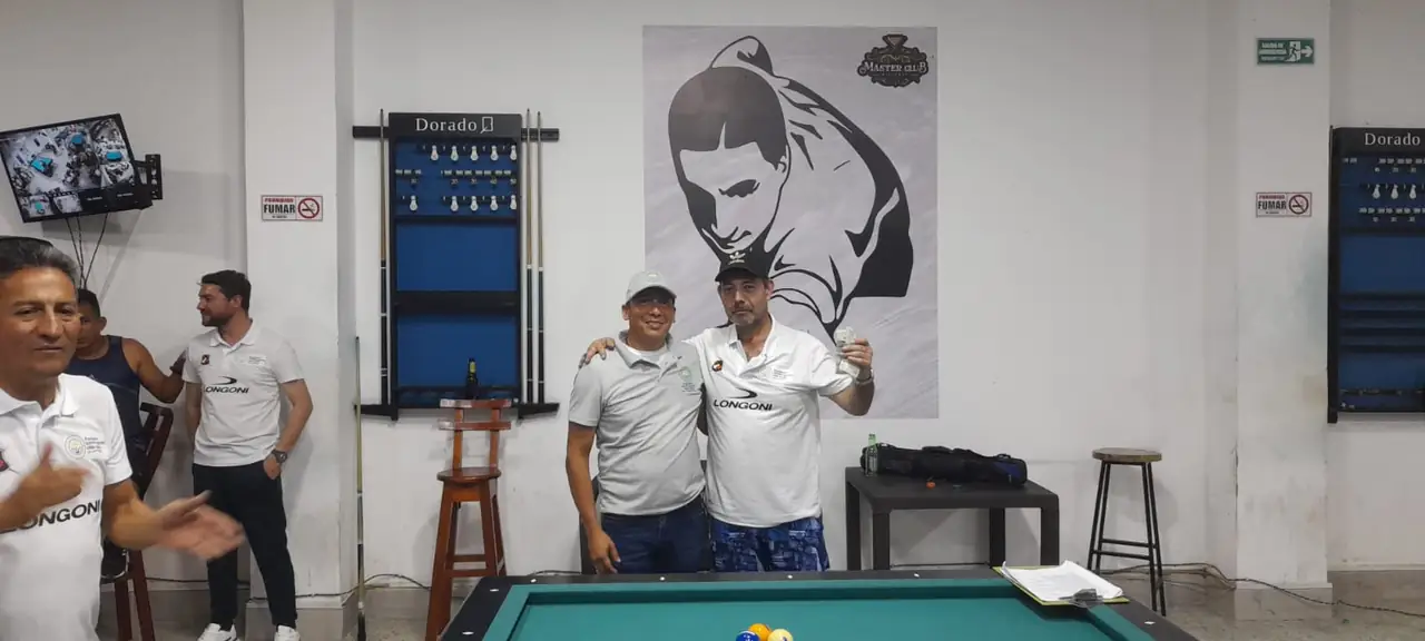 Dos participantes se abrazan junto a la mesa durante la premiación