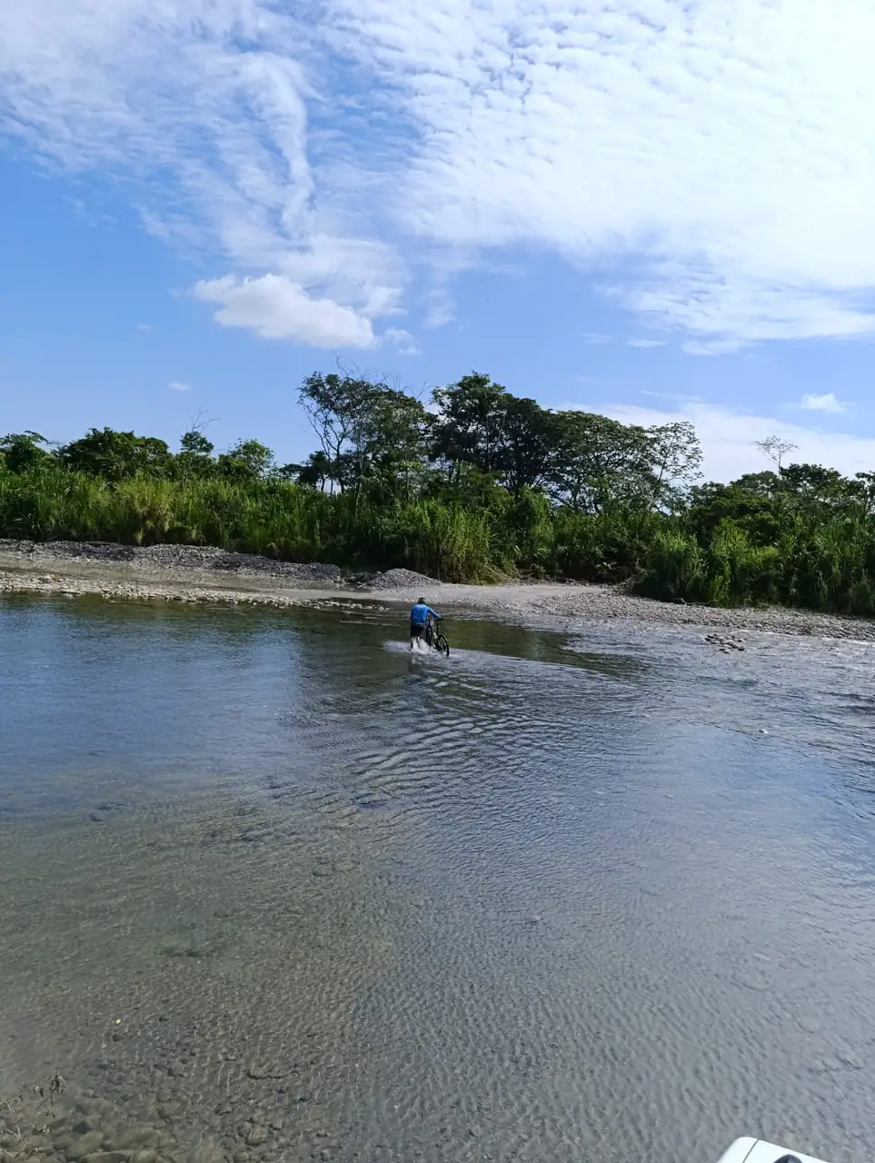 Ciclista cruzando un río ancho bajo el cielo del Meta