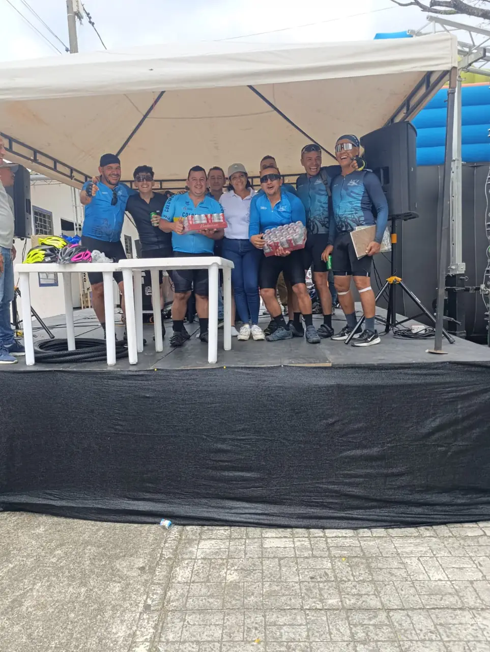 Grupo de ciclistas premiados en la tarima con sus premios en la mano
