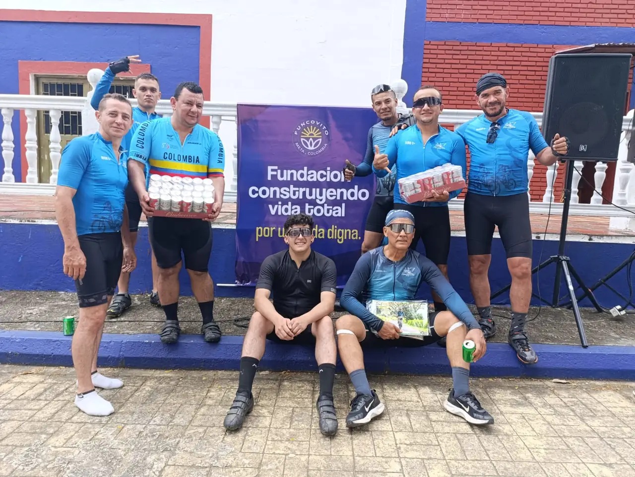 Ciclistas con sus premios frente al pendón de la Fundación Construyendo Vida Total