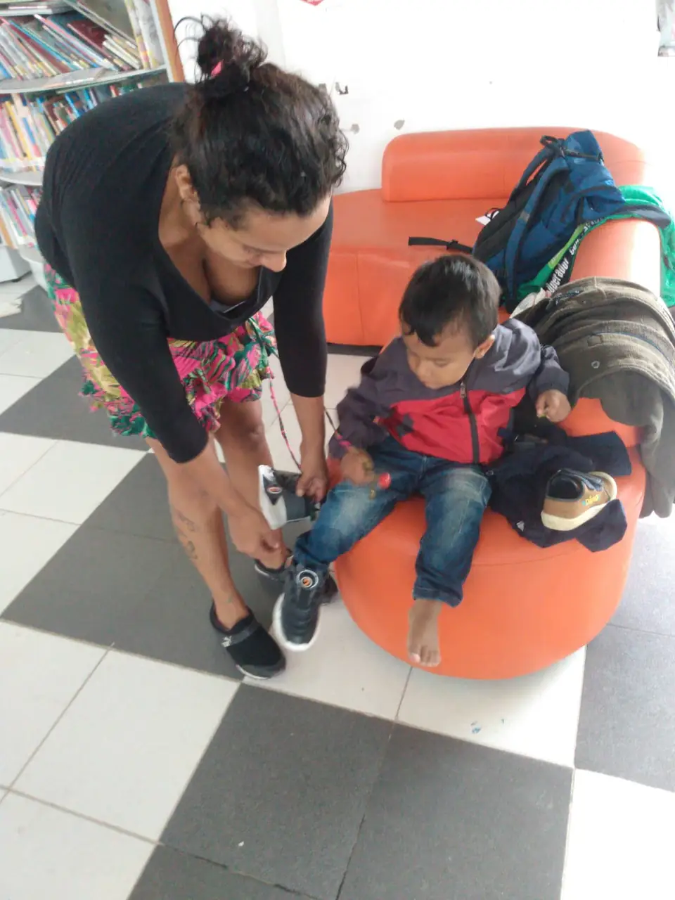 Una madre le prueba los zapatos nuevos a su hijo pequeño