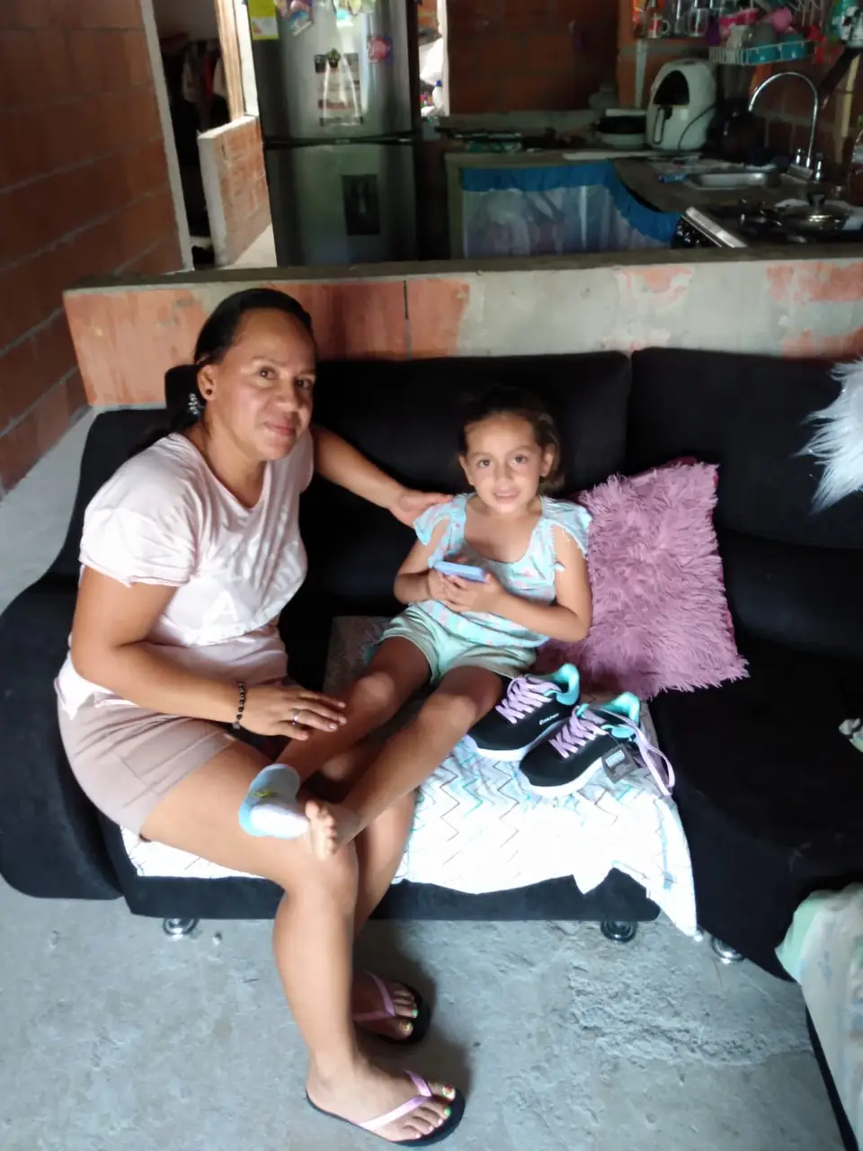 Una madre y su hija sentadas en casa con los tenis nuevos de la niña