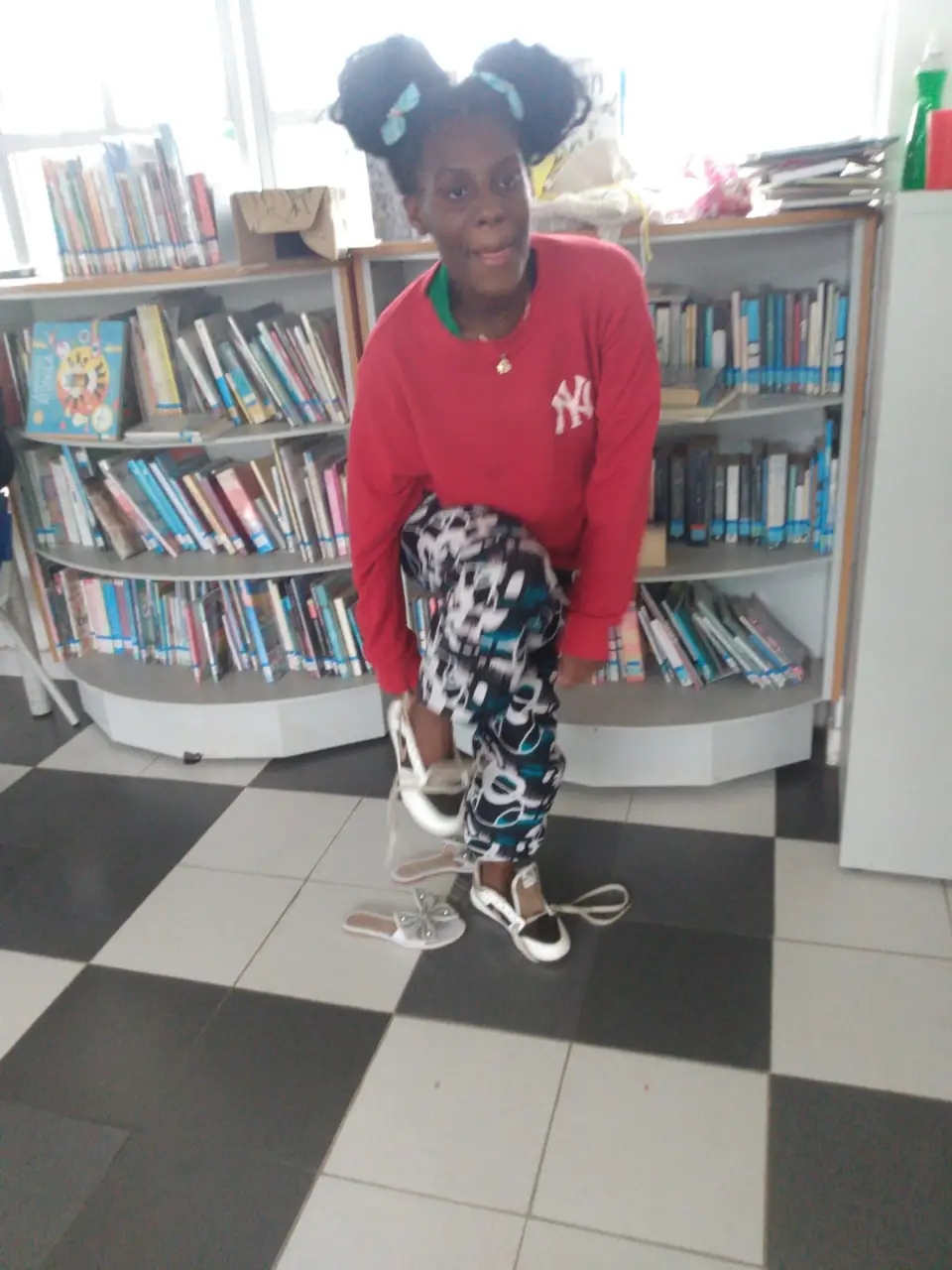 Una niña sonríe mientras se prueba sus tenis nuevos en la biblioteca