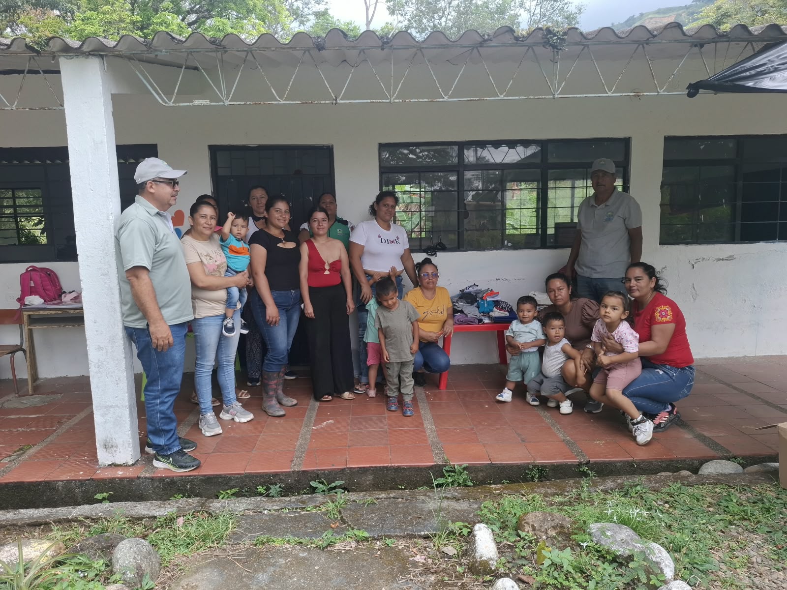 Integrantes de la fundación con madres, niñas y niños de las familias beneficiadas, frente a la mesa con la ropa donada